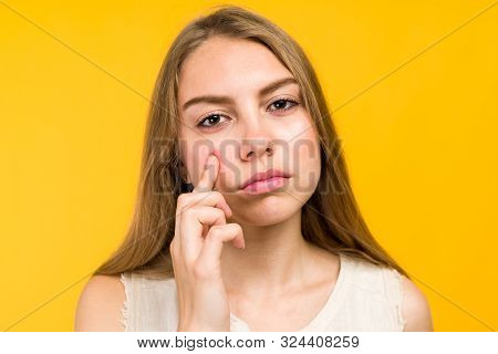 Portrait Of Sad Teen Gerl Touching Her Face And Looking For Acne On Yellow Background