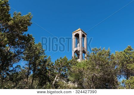 Wooden Bell Tower Framed By Tree Branches Against A Blue Sky