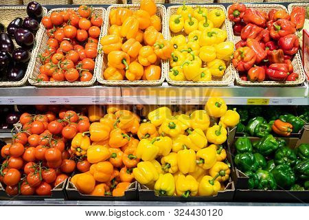 Grocery Store Counter With Wicker Baskets And Lug Boxes With Fresh Tomatoes, Squash, Orange And Yell
