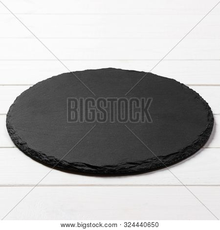 Black Round Plate On Wooden Background, Top View, Copy Space