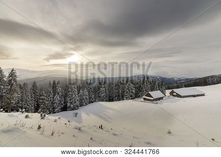 Winter Mountain Landscape. Old Wooden Houses On Snowy Clearing On Background Of Mountain Ridge, Spru