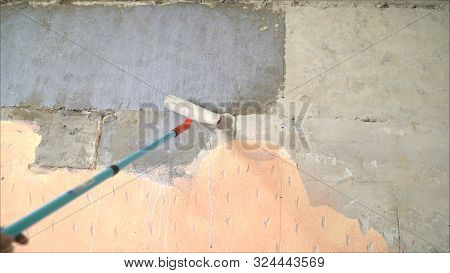 The Process Of Priming A Brick Wall. A Primer Solution Is Applied To A Brick Wall Using A Roller Thu
