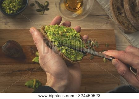 Close Up Of A Chef Hands Making Avocado Sandwich On A Wooden Table. Toast With Hummus. Man Making Br