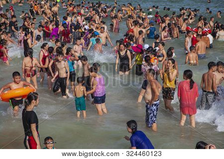 Many Chinese Tourists On The Beach Swim In The Waves