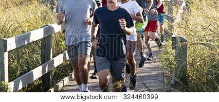 A High School Boys Cross Country Team Is Running On The Fire Island Lighthouse Boardwalk Sourrounded