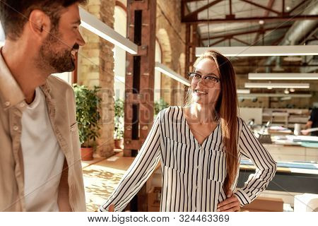 Office Life. Two Modern Young People Talking About Something While Standing In The Creative Office