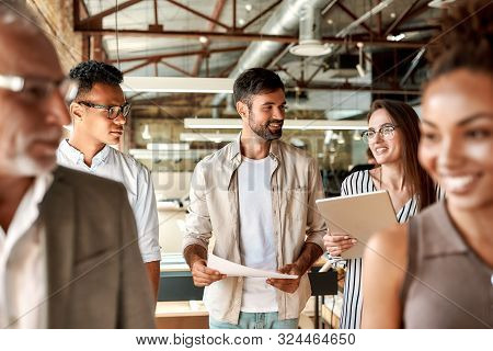 Office Life. Modern Business People Discussing Something And Smiling While Walking Through The Offic