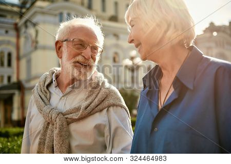 You Are Making Me Happy. Beautiful Elderly Couple Looking At Each Other And Smiling While Spending T
