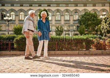 Love Has No Age Limit. Beautiful Elderly Couple Holding Hands And Looking At Each Other With Smile W