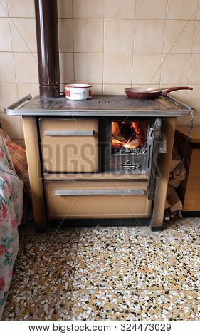 Very Old Wood Stove With A Blazing Fire And The Pots With Hot Items