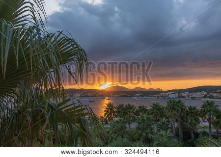 Panoramic Sunset View Against Mountains And Sky With Thick Clouds. Palm Trees In The Foreground