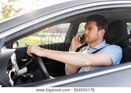 transport, vehicle and people concept - smiling man or driver driving car and calling on smartphone