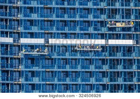 Construction Of A Large Residential Complex Of Glass On A Sunny Day. Three Hanging Construction Crad