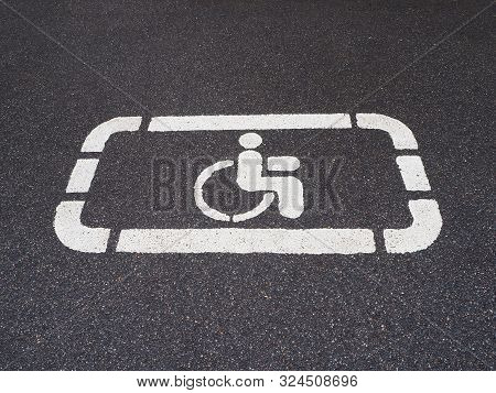 White Handicapped Symbol Of Wheelchair Painted On Asphalt On A Parking Lot, Sign Of Parking Space Fo