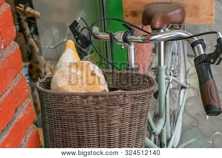 Bread In A Wicker Basket On A Bicycle Near A Brick Wall Close-up