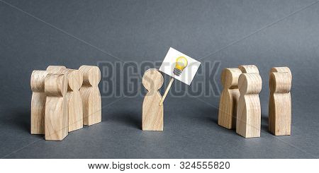 A Man With A Poster With A Picture Of The Idea Bulb Refers To A Crowd Of People. The Concept Of Prop