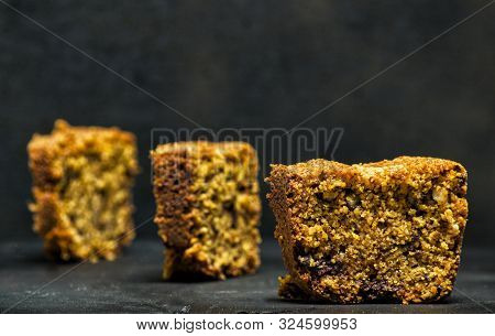 Homemade Tart Slices On A Black Background With Chocolate, Italian Amaretti Cookies, Nuts And Yogurt