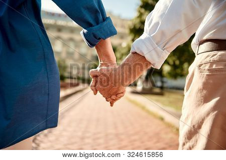 You And Me Forever. Close-up Of Elderly Couple Holding Hands While Walking Together Outdoors