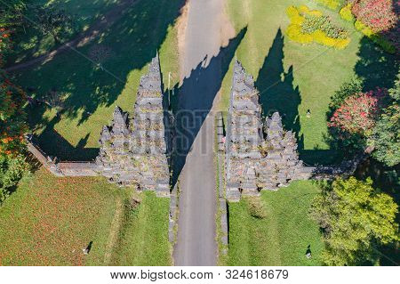 Aerial View Of Bali Handara. The Hindu Temple With Ancient Gate With Pathway In Park Garden At Noon.