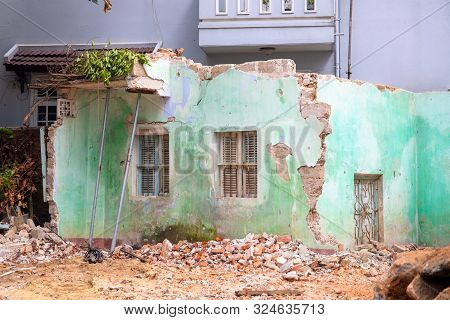Broken House After Earthquake. Old Building Deconstruction With New Modern Building On Background. D