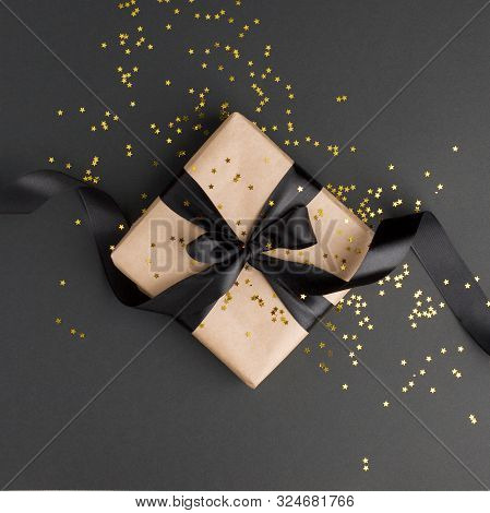 Gift Or Present Box And Gold Stars Confetti On Black Table Top View. Flat Lay Composition For Birthd