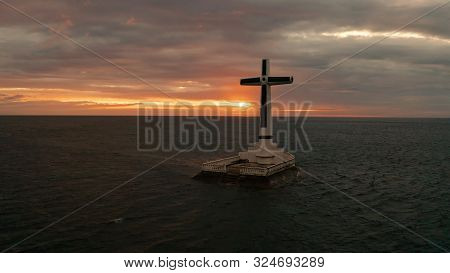 Catholic Cross In Sunken Cemetery In The Sea At Sunset, Aerial Drone. Colorful Sky During The Sunset