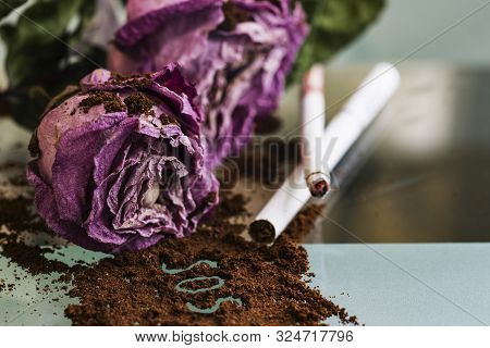 Faded Roses Lie On The Glass Surface. Next To The Roses Are A Cigarette And A Cigarette Butt. Before