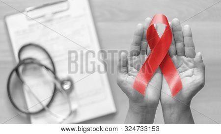 World Aids Day And National Hiv/aids And Ageing Awareness Month With Red Ribbon On Woman Hand Suppor