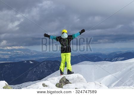 Back View Of A Cheerful Skier With Raised Hands As A Symbol Of Victory Looking At A Panoramic View O