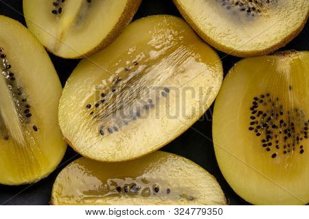 closeup of cut gold juicy kiwifruit on a black plate