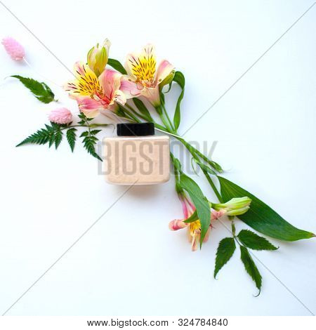 Jar With Flesh-colored Loose Powder And Alstroemeria Flowers.