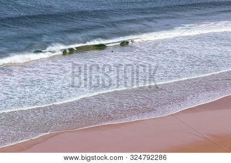 Surfers In The Waves Off Mawgan Porth Beach, North Cornwall, Uk