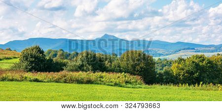 Mountain Ridge With High Peak. Sunny Weather In Early Autumn With Fluffy Clouds On The Sky. Trees On