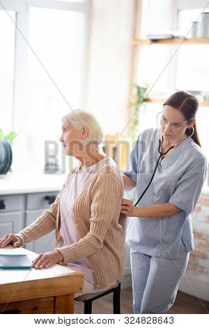 Nurse Examining Retired Lady Feeling Sick And Tired