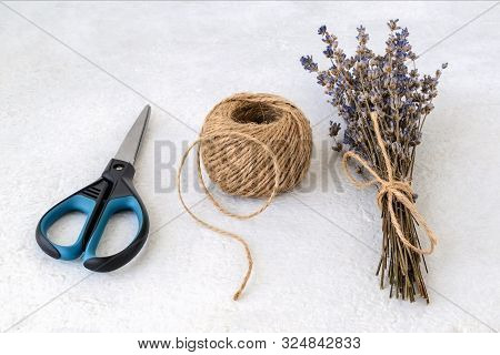 Natural Hemp Cord Ball, Scissors And Dry Lavender Bouquet On A Rough White Surface. Roll Of Jute Str