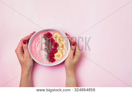 Womans Hands Holsing A Smoothie Bowl With Bananas And Raspberies