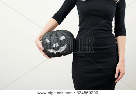 Cropped Image Of Slim Young Woman In Black Bodycon Dress Holding Plastic Pumpkin Painted Like Jack-o