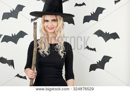 Portrait Of Young Attractive Blond Woman In Bodycon Dress And Pointy Hat Standing With Broom