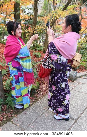 Kyoto, Japan - November 24, 2016: Women In Kimono Take Photos With Autumn Leaves Of Maple (momiji) I