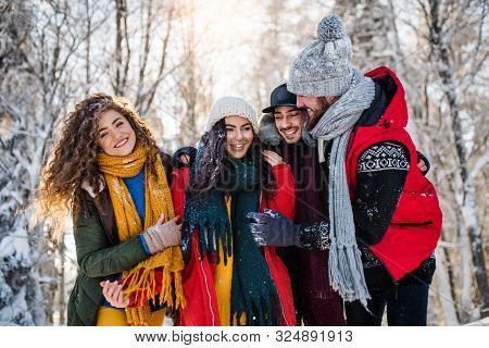 A Group Of Young Friends On A Walk Outdoors In Snow In Winter Forest.