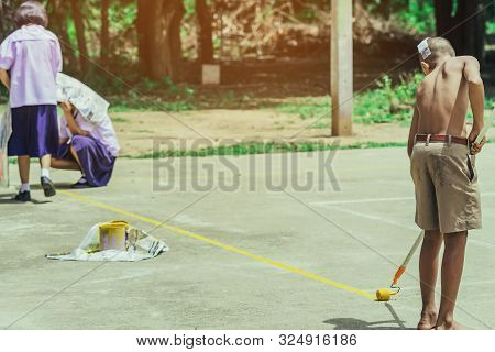 Male Students Use Small Paint Rollers To Paint Yellow Lines On The Cement Floor For Sepak Takraw Tra