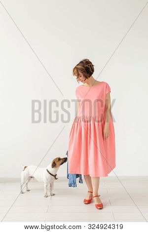Pet And People Concept - Young Woman In Pink Dress With Jack Russell Over The White Background