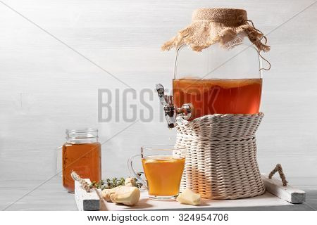 Fresh Homemade Kombucha Fermented Tea Drink In A Jar With Faucet And In A Cup And In Mug On A White 