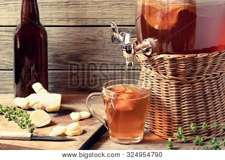 Fresh Homemade Kombucha Fermented Tea Drink In Jar With Faucet And In Cup And Bottle On Wooden Backg