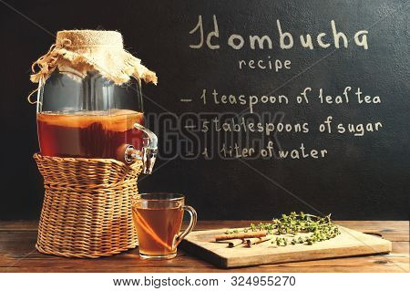 Fresh Homemade Kombucha Fermented Tea Drink In A Jar With Faucet And In A Cup And Recipe On A Dark W