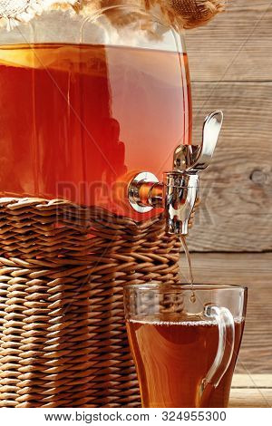 Fresh Homemade Kombucha Fermented Tea Drink In Jar With Faucet And In Cup On Wooden Background. Vert