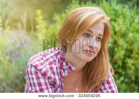 Saddened Smiling Attractive Young Woman Is Looking Ahead Outdoors.