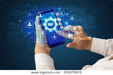 Female hand holding smartphone with IMF abbreviation, modern technology concept