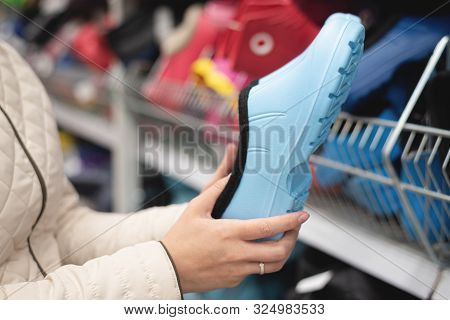 Woman Is Buying A New Galoshes Shoes In A Shop.