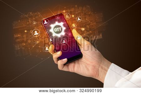 Female hand holding smartphone with OTT abbreviation, modern technology concept